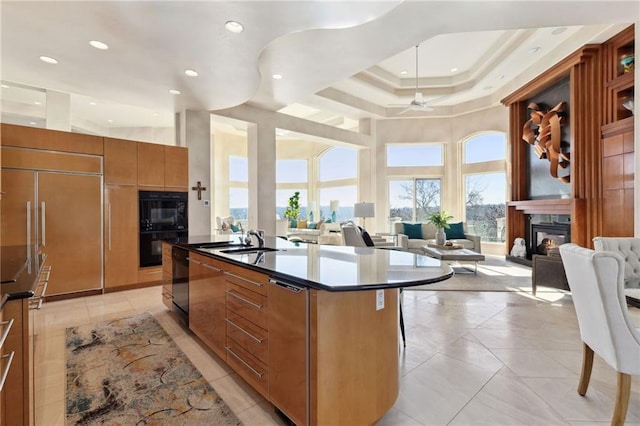 kitchen featuring open floor plan, modern cabinets, a glass covered fireplace, and a center island