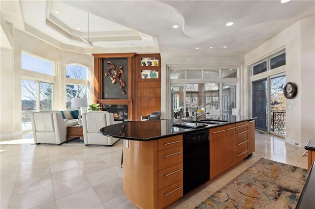 kitchen featuring black dishwasher, a glass covered fireplace, dark countertops, and a sink