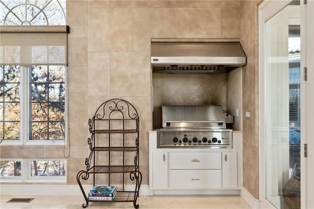 kitchen with white cabinets, wall chimney range hood, visible vents, and decorative backsplash