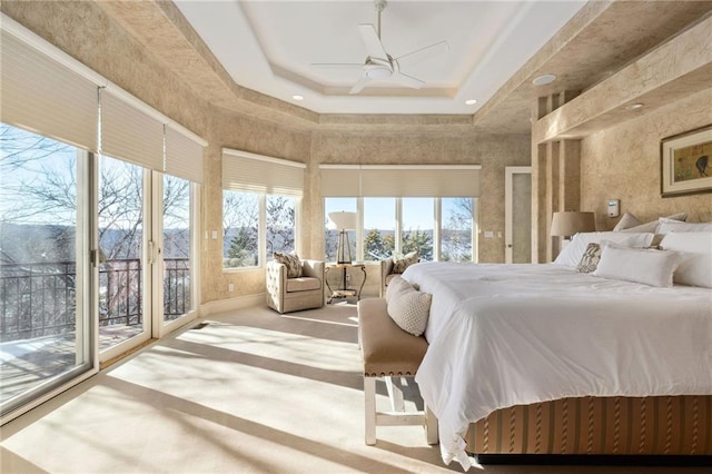 bedroom with access to exterior, a raised ceiling, a towering ceiling, a ceiling fan, and carpet flooring