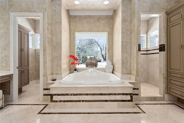 bathroom featuring marble finish floor, a garden tub, and plenty of natural light