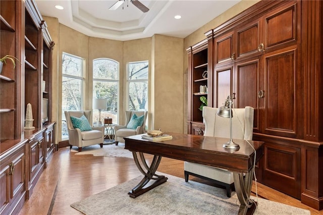 home office featuring a ceiling fan, light wood-type flooring, a tray ceiling, and recessed lighting