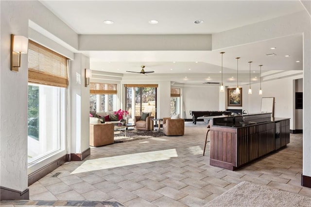 kitchen featuring open floor plan, an island with sink, dark countertops, a kitchen bar, and decorative light fixtures