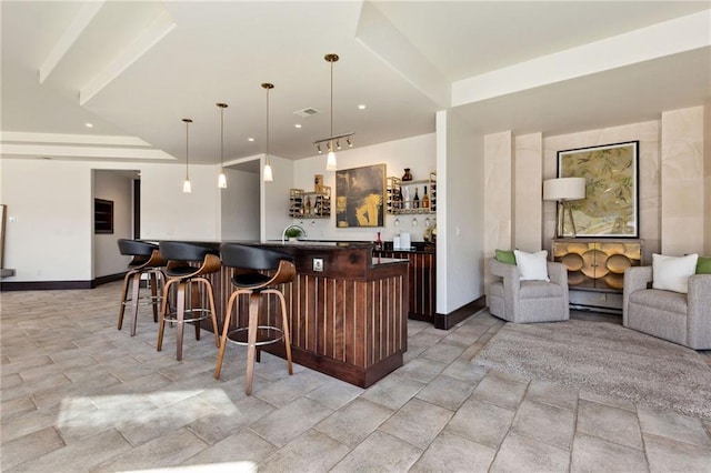 bar featuring wet bar, pendant lighting, a sink, and baseboards