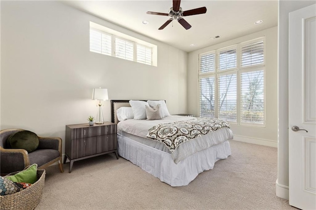 bedroom featuring light carpet, visible vents, baseboards, and multiple windows