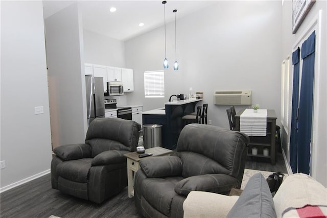 living area featuring baseboards, dark wood finished floors, recessed lighting, an AC wall unit, and a towering ceiling