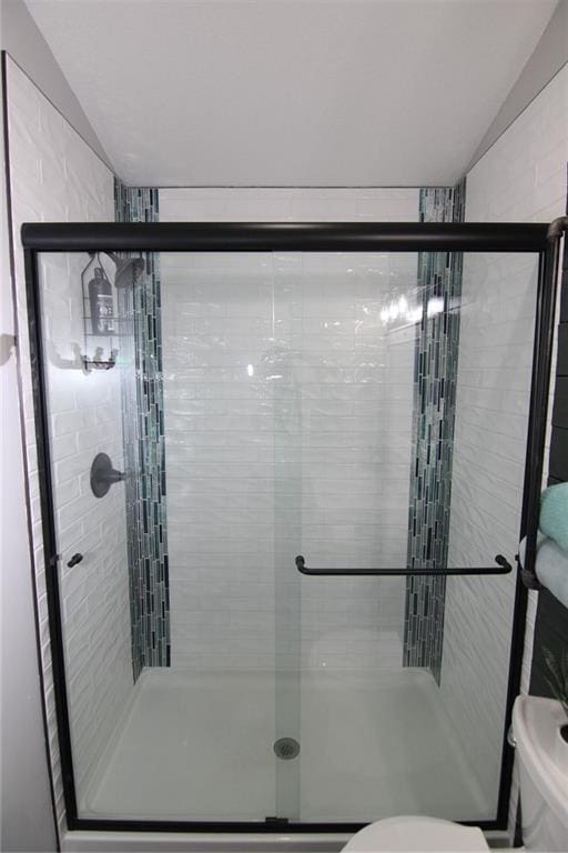 bathroom featuring a shower stall, toilet, and vaulted ceiling