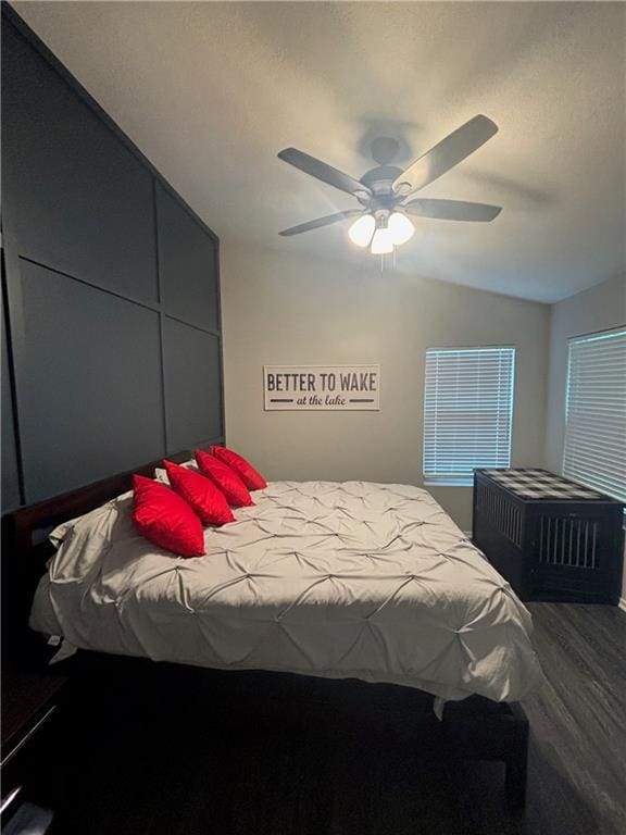 bedroom with a textured ceiling, lofted ceiling, wood finished floors, and ceiling fan