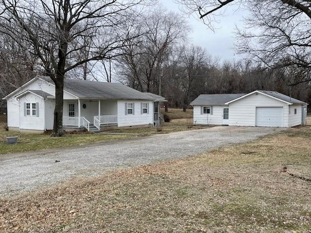 view of front of property featuring covered porch, driveway, an outdoor structure, and a garage