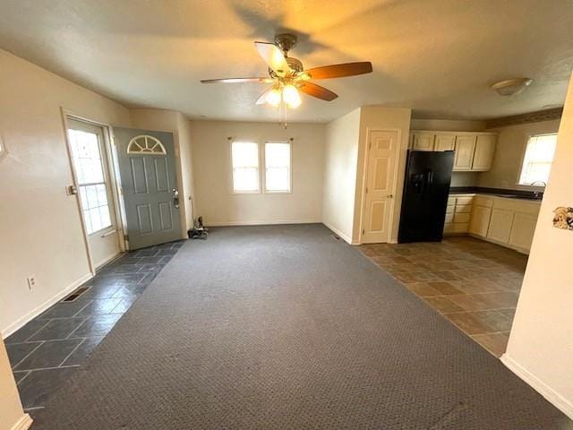 interior space with visible vents, dark carpet, a ceiling fan, and baseboards