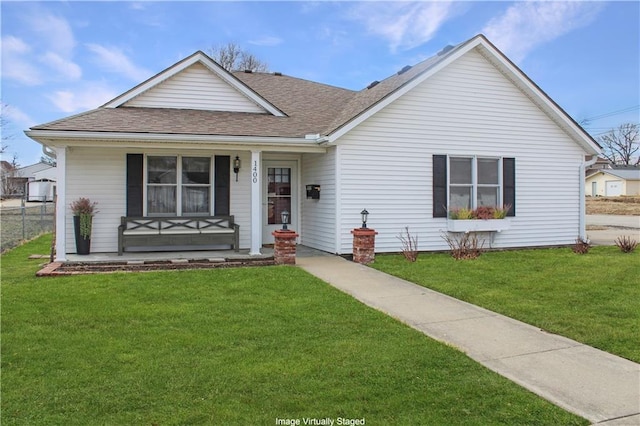 ranch-style house featuring a shingled roof, covered porch, and a front lawn