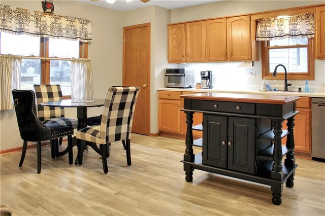 kitchen with light wood-type flooring, a wealth of natural light, light countertops, and a sink