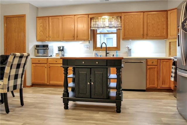 kitchen featuring a sink, light wood-style floors, light countertops, and dishwasher