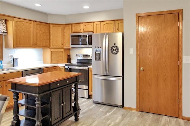 kitchen featuring stainless steel appliances, recessed lighting, light countertops, and light wood finished floors