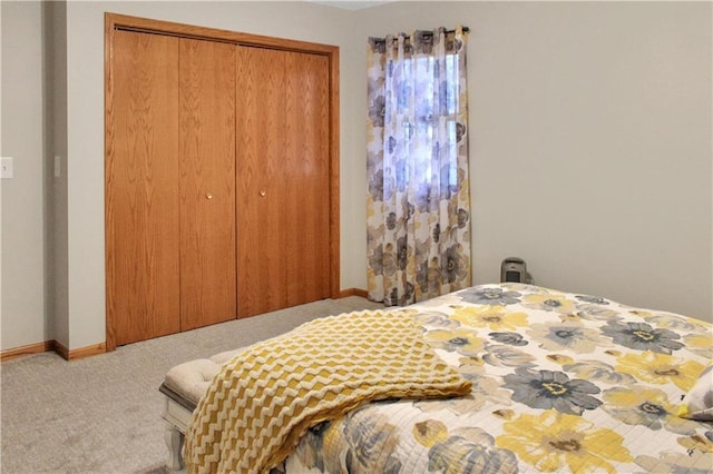 carpeted bedroom featuring a closet and baseboards