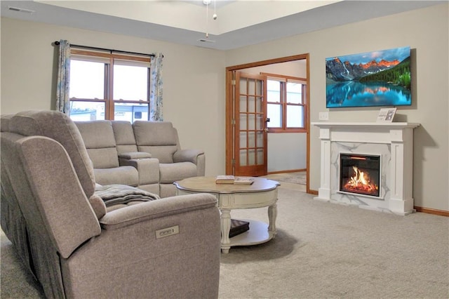 carpeted living room featuring baseboards, a fireplace, and visible vents