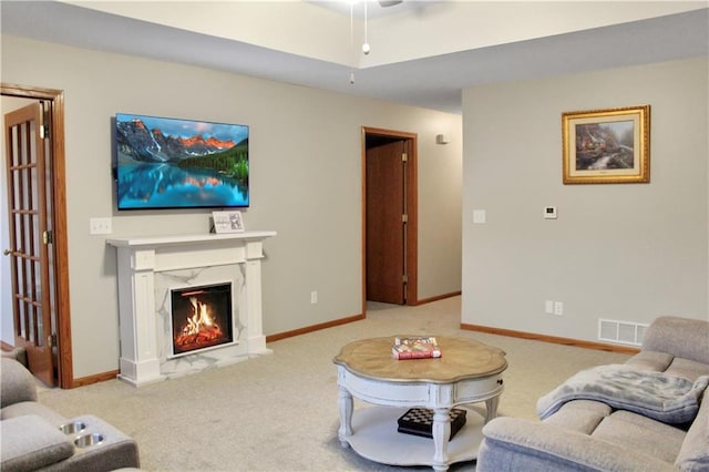 carpeted living room with a high end fireplace, visible vents, and baseboards