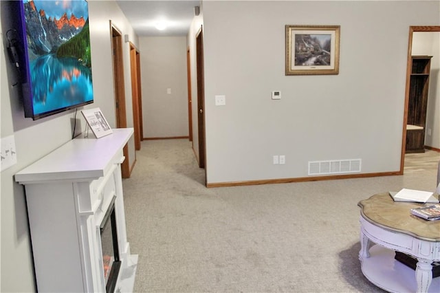 corridor with light carpet, baseboards, and visible vents