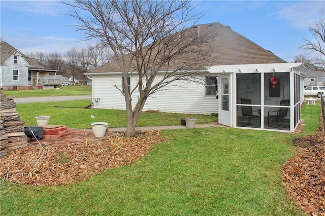 back of property with a sunroom, a lawn, and roof with shingles