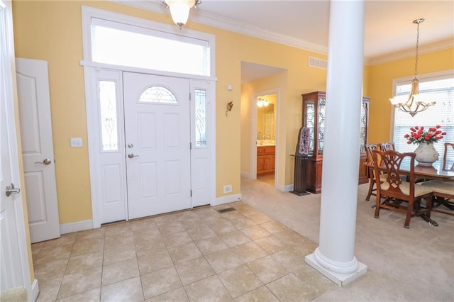 entryway featuring light carpet, visible vents, baseboards, decorative columns, and crown molding