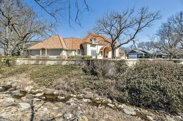 view of front of property with a tiled roof, stucco siding, and fence