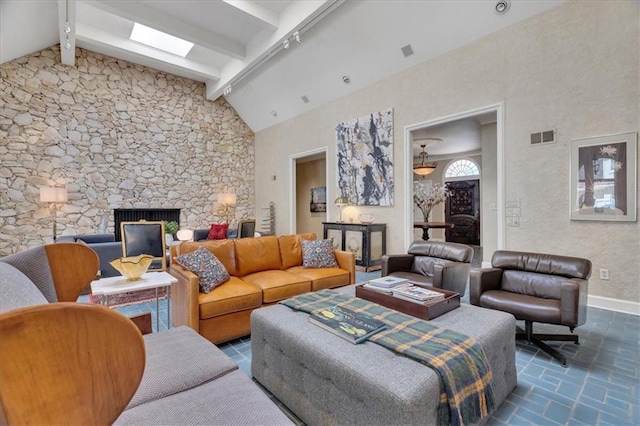 living room featuring beam ceiling, visible vents, a fireplace, and baseboards