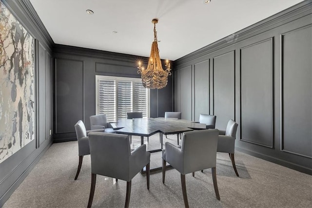 dining room featuring light carpet, an inviting chandelier, ornamental molding, and a decorative wall