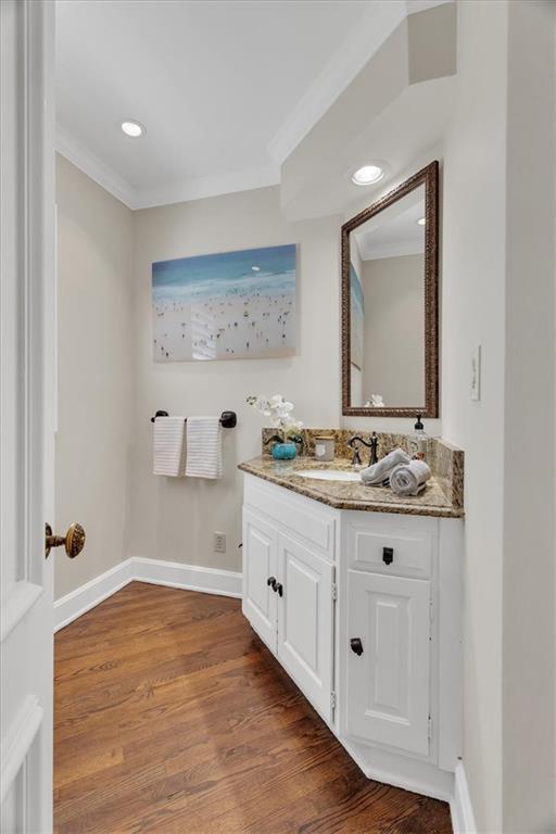 bathroom featuring vanity, wood finished floors, baseboards, recessed lighting, and crown molding