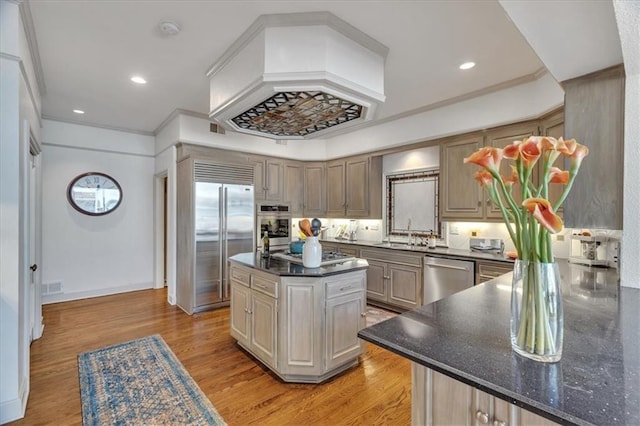 kitchen with a kitchen island, crown molding, stainless steel appliances, and light wood-type flooring