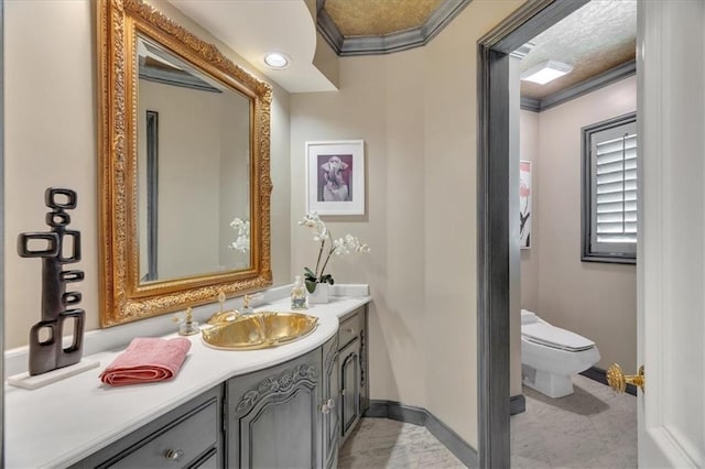 bathroom with vanity, toilet, crown molding, and baseboards