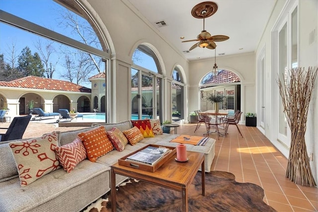 sunroom / solarium with visible vents, a healthy amount of sunlight, and a ceiling fan