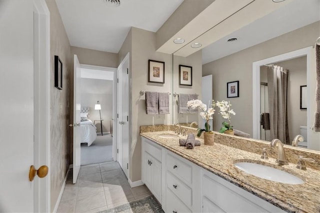 full bathroom featuring double vanity, connected bathroom, baseboards, and a sink