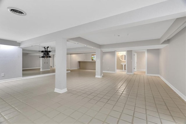 finished below grade area featuring light tile patterned floors, visible vents, and baseboards