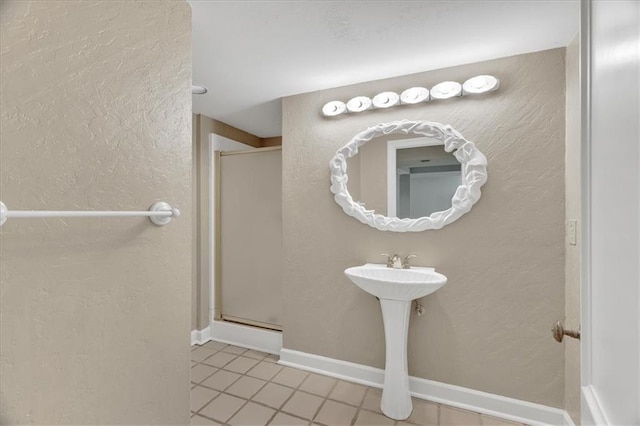 full bathroom featuring baseboards, a shower stall, and a textured wall