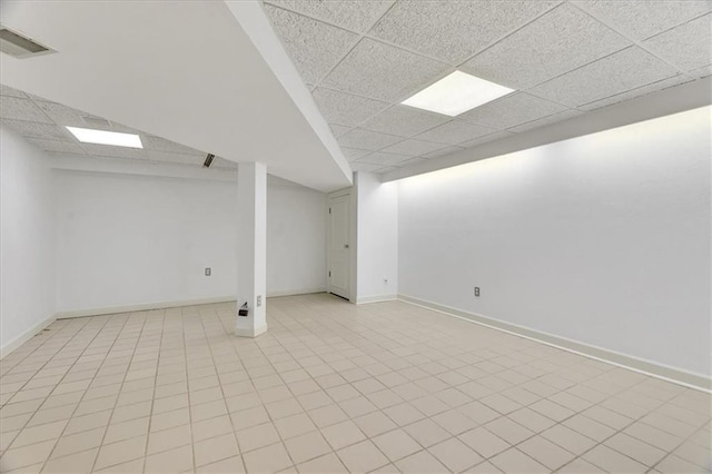 finished basement with visible vents, baseboards, and a drop ceiling