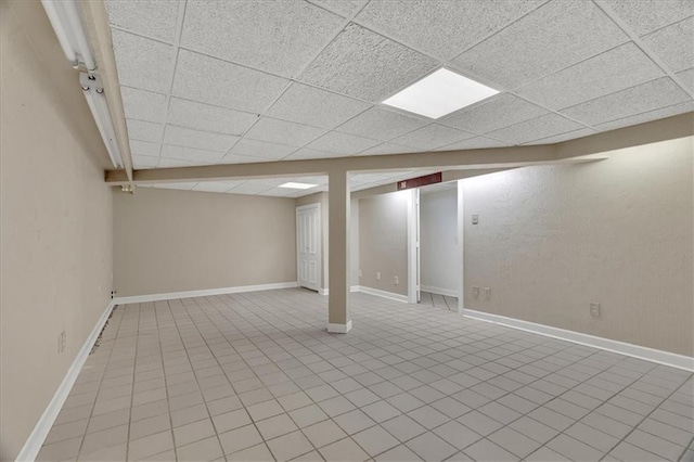 finished basement featuring baseboards and a drop ceiling