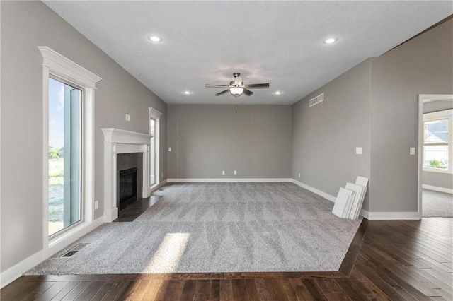 unfurnished living room with dark wood-style floors, a high end fireplace, visible vents, and baseboards