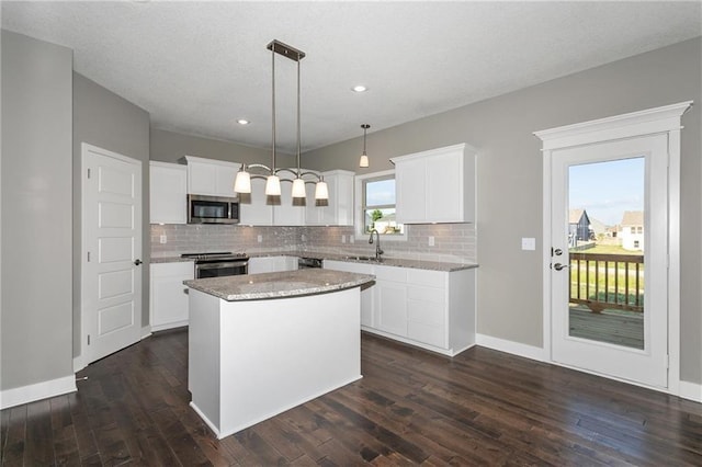 kitchen with tasteful backsplash, a kitchen island, appliances with stainless steel finishes, dark wood-type flooring, and a sink