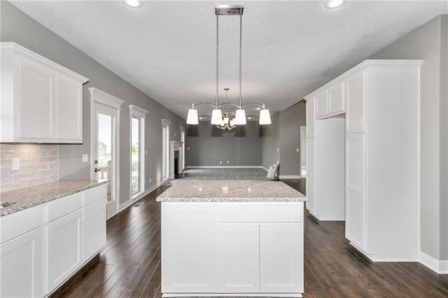 kitchen with backsplash, white cabinets, dark wood-type flooring, and a center island