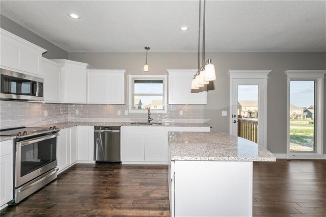 kitchen featuring dark wood finished floors, backsplash, appliances with stainless steel finishes, white cabinetry, and a sink