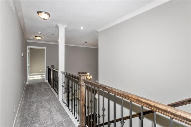 hall featuring carpet floors, crown molding, decorative columns, a textured ceiling, and baseboards