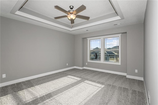 carpeted spare room with baseboards, a raised ceiling, and a textured ceiling