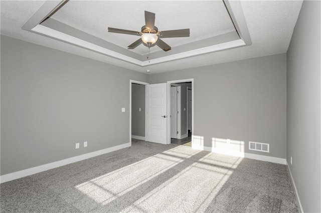 unfurnished bedroom with a raised ceiling, visible vents, a textured ceiling, and baseboards