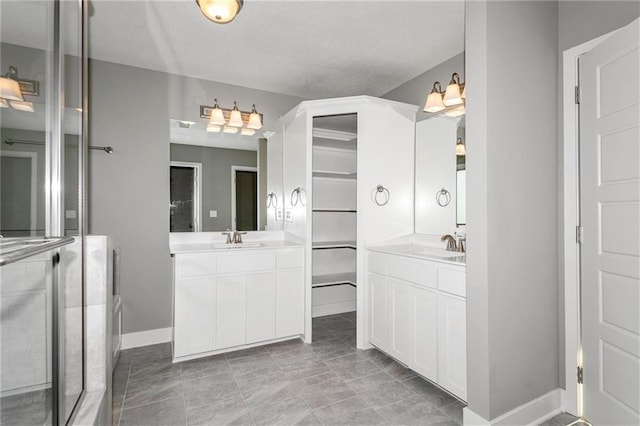 bathroom featuring two vanities, a sink, and baseboards