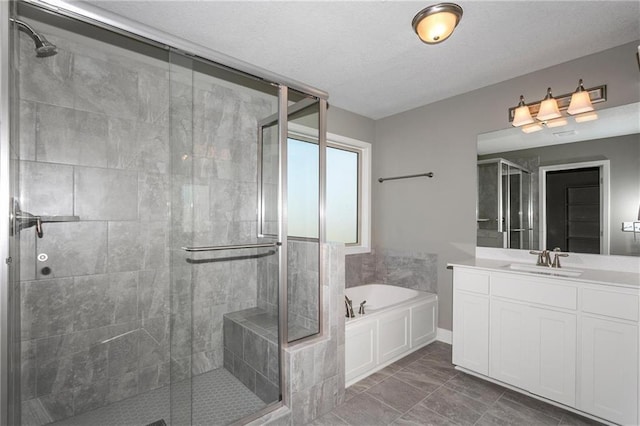 full bathroom featuring a garden tub, a shower stall, a textured ceiling, and vanity