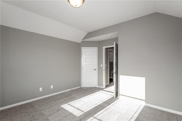 empty room with carpet floors, vaulted ceiling, and baseboards