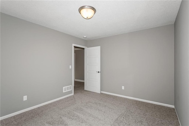 empty room with carpet, baseboards, visible vents, and a textured ceiling