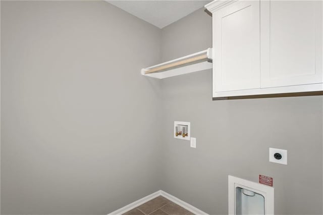 laundry area featuring hookup for an electric dryer, dark tile patterned floors, washer hookup, baseboards, and cabinet space