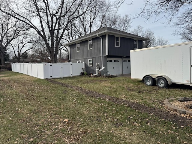 view of side of home with a gate, a garage, a yard, and fence