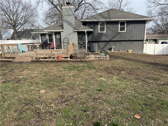 back of property with a yard, fence, a chimney, and a wooden deck